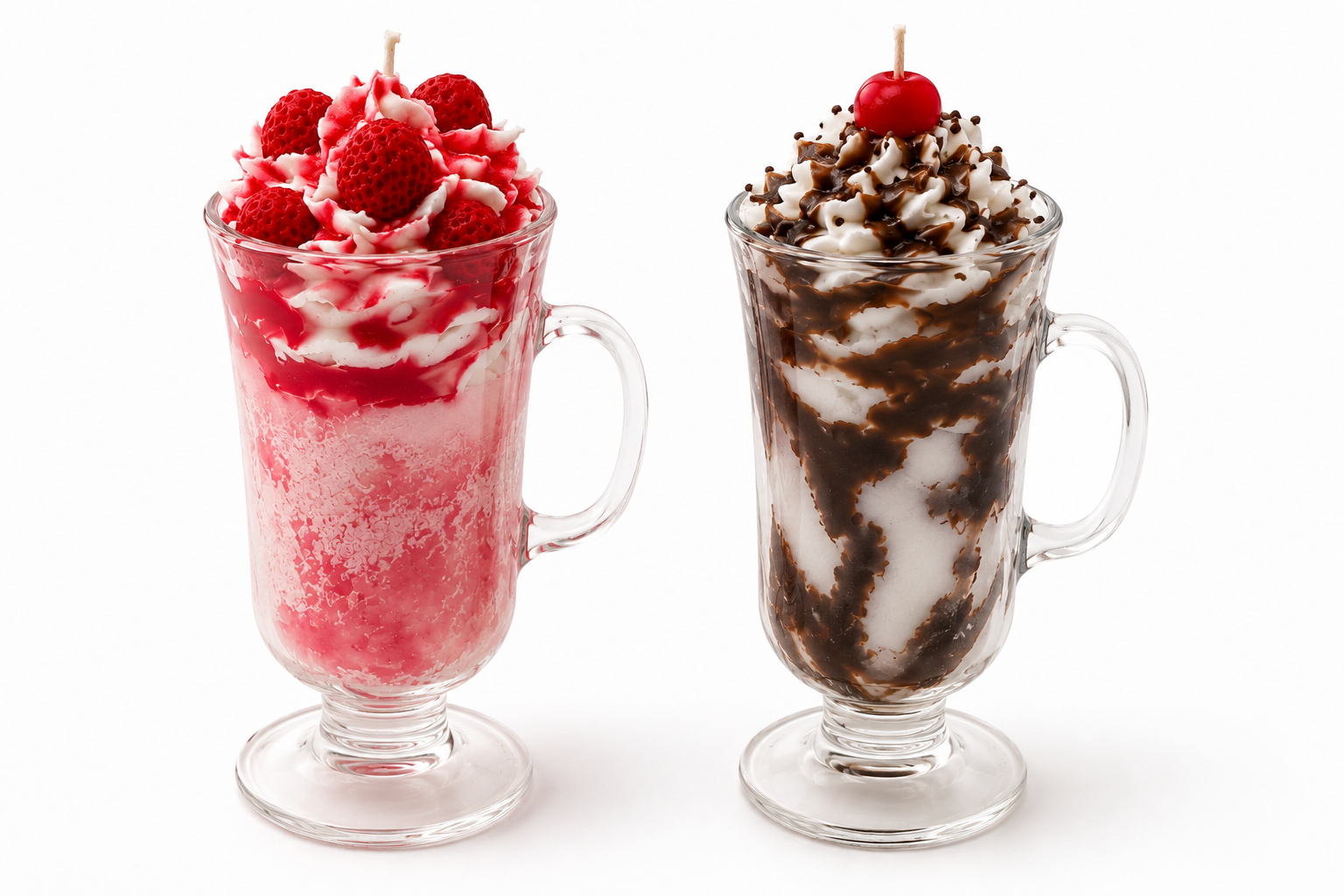 Two tall clear glass mugs filled with whipped dessert on a white background. The left mug contains a pink-red frozen drink topped with whipped cream, raspberries, and a cherry.